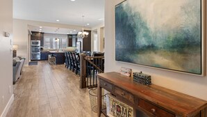 A modern kitchen with dark cabinetry, stainless steel appliances, and a dining area with bar stools. - Paradise Private Pool Retreat #17 6 Bedroom Home (Ivins)