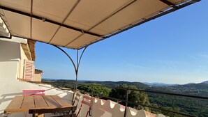 A terrace with a wooden table and pink chairs, overlooking a scenic landscape with hills and a clear sky. - Maison de Village Avec vue Exceptionnelle, Presqu'île de Saint Tropez (Gassin)