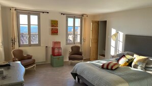 A bedroom with a bed, two armchairs, a small table, and a window with a view. - Maison de Village Avec vue Exceptionnelle, Presqu'île de Saint Tropez (Gassin)