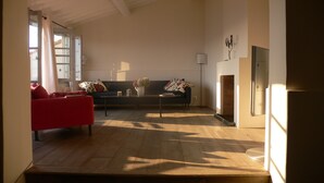 A living room with a red sofa, a black sofa, and a coffee table. There is a vase with flowers on the coffee table. - Maison de Village Avec vue Exceptionnelle, Presqu'île de Saint Tropez (Gassin)