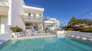 Une maison moderne à deux étages dotée d’une piscine, d’un espace salon extérieur et d’un patio couvert.
