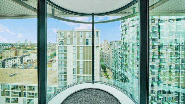 A modern interior with a curved ceiling, large windows offering a view of surrounding high-rise buildings. - Morden2bed 2bath apartment Canary Wharf - upto 5ppl (London)