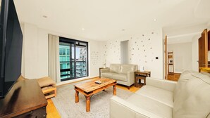 A modern living room with a sofa, a wooden coffee table, and a TV. - Morden2bed 2bath apartment Canary Wharf - upto 5ppl (London)