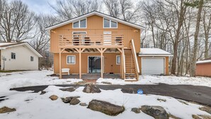 Et toetagers træhus med balkon, garage og indkørsel.