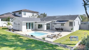 Une maison moderne à deux étages, dotée d’une piscine, de mobilier de jardin et d’une cour arrière clôturée.