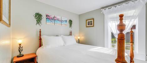 A neatly made bed with white linens, a wooden headboard, and two bedside lamps.