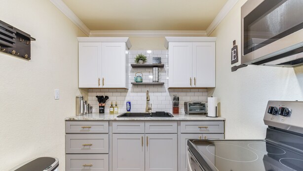 A kitchen with white cabinets, a stainless steel oven, and a microwave. - 2 Mi to Dtwn: Chic Waco Studio w/ Fire Pit! (Waco)