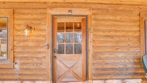 A wooden cabin door with a glass panel, a bell, and a light fixture on the wall. - Cropwell Cabin w/ Fire Pit, Near Logan Martin Lake (Cropwell)