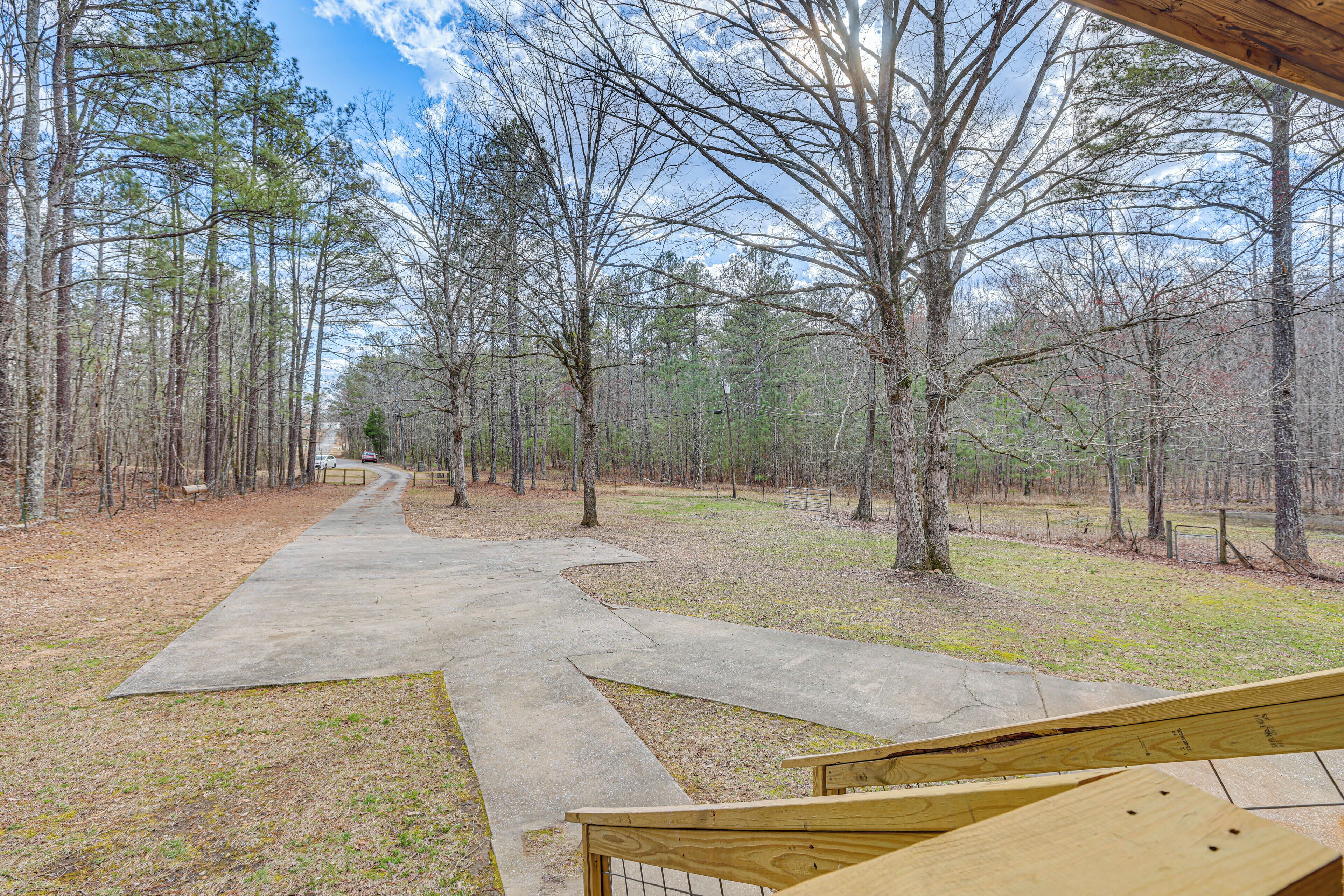A concrete pathway leading through a wooded area with benches and a wooden structure in the foreground.