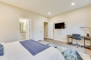 Une chambre d’hôtel comprenant un lit, un bureau avec une chaise, une télévision et deux portes donnant sur d’autres chambres.