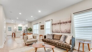 A spacious living area with a sofa, coffee table, and a dining area in the background.