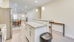 A modern kitchen with white cabinetry, granite countertops, and pendant lighting.
