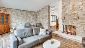 A living room with a stone wall, a fireplace, a gray sofa, and a wooden cabinet.