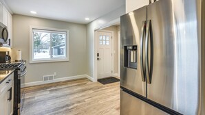A modern kitchen with stainless steel appliances, a large window, and hardwood flooring. - Riverfront Michigan Cottage w/ Fire Pit & Kayaks! (Beaverton)