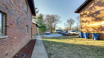 A brick building with a paved driveway and a grassy area with trash bins.