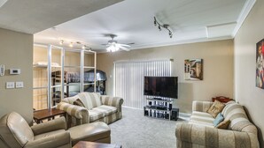 Un salon avec un ventilateur de plafond, un téléviseur et un canapé.