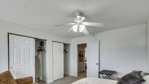 Une chambre à coucher avec un lit, un ventilateur de plafond et un dressing.