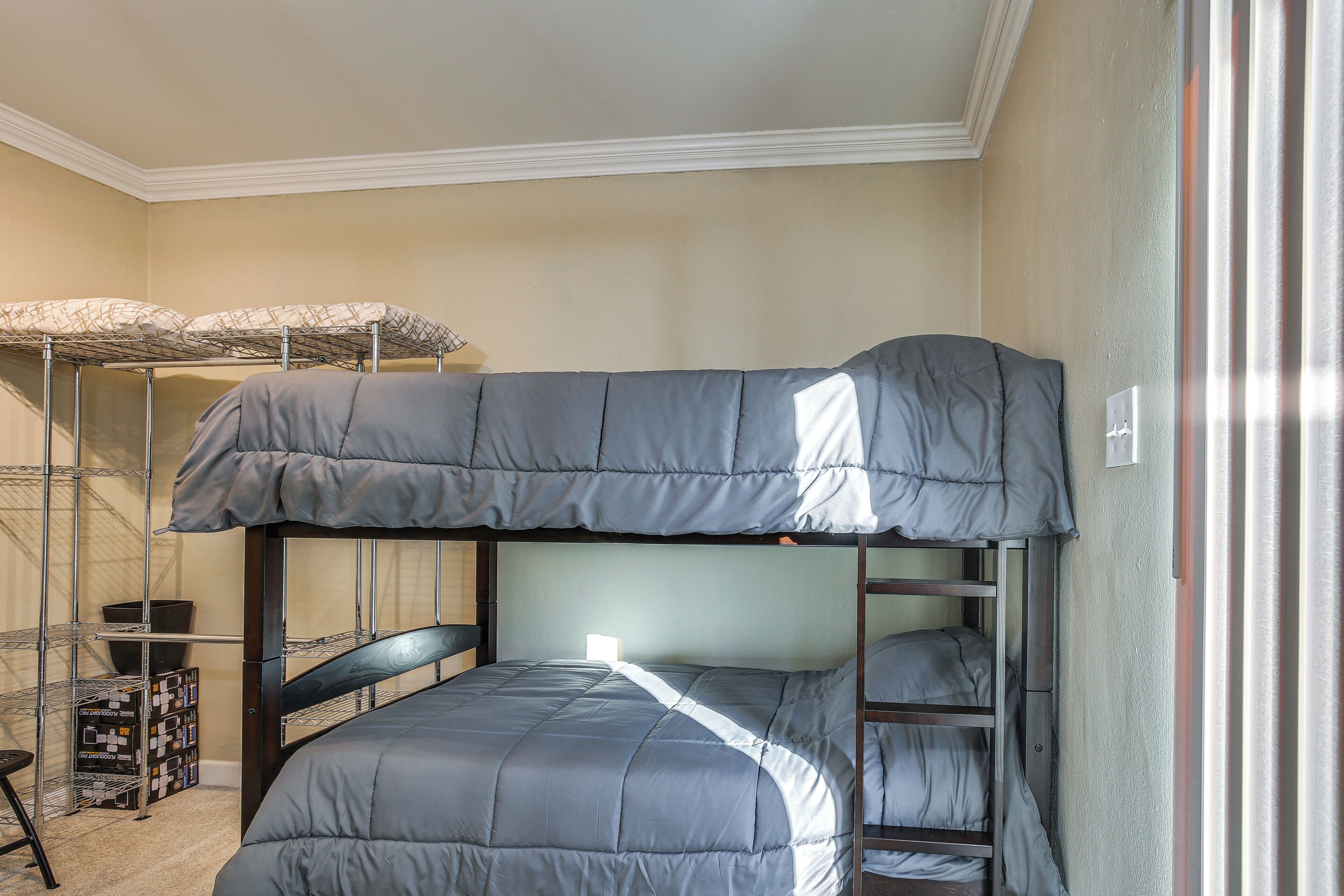 A bunk bed with a grey mattress and a metal ladder.