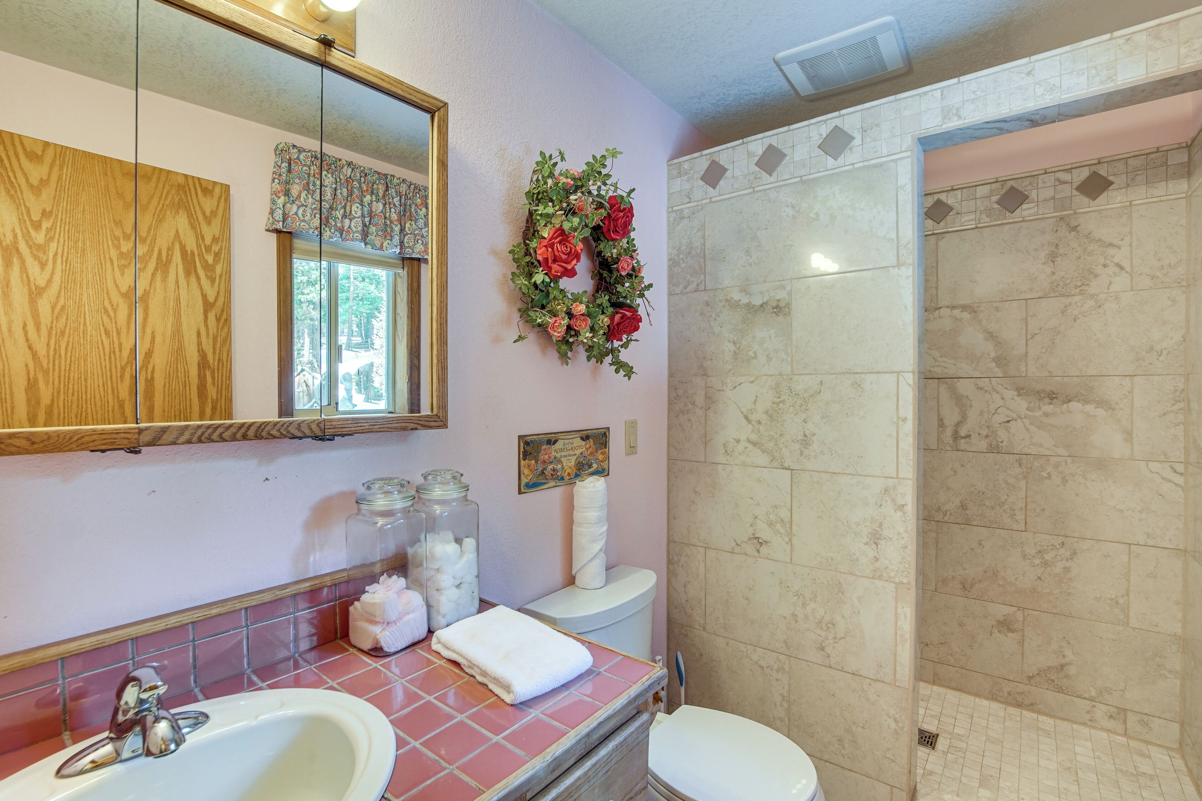 A bathroom with a sink, mirror, toilet, and shower.