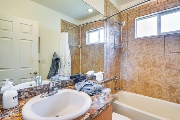 A bathroom with a sink, mirror, shower, and towel rack.