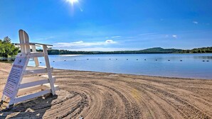Una playa con un letrero de madera y un cielo azul despejado.