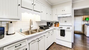 A kitchen with white cabinets, a stove, a sink, and a digital scale. - Peaceful Cottage w/ Yard: 2 Mi to Kentucky Lake! (Stewart)
