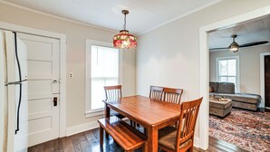 A dining area with a wooden table and chairs, a hanging light fixture, and a view into a living room with a sofa and a patterned rug. - Peaceful Cottage w/ Yard: 2 Mi to Kentucky Lake! (Stewart)