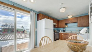 A kitchen with wooden cabinets, a white refrigerator, a microwave, and a dishwasher. - Dog-friendly Montana Home w/ Deck & Fenced-in Yard (Dillon)