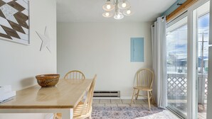 A dining area with a wooden table, chairs, a decorative bowl, a patterned rug, a ceiling light fixture, and a view through a glass door. - Dog-friendly Montana Home w/ Deck & Fenced-in Yard (Dillon)