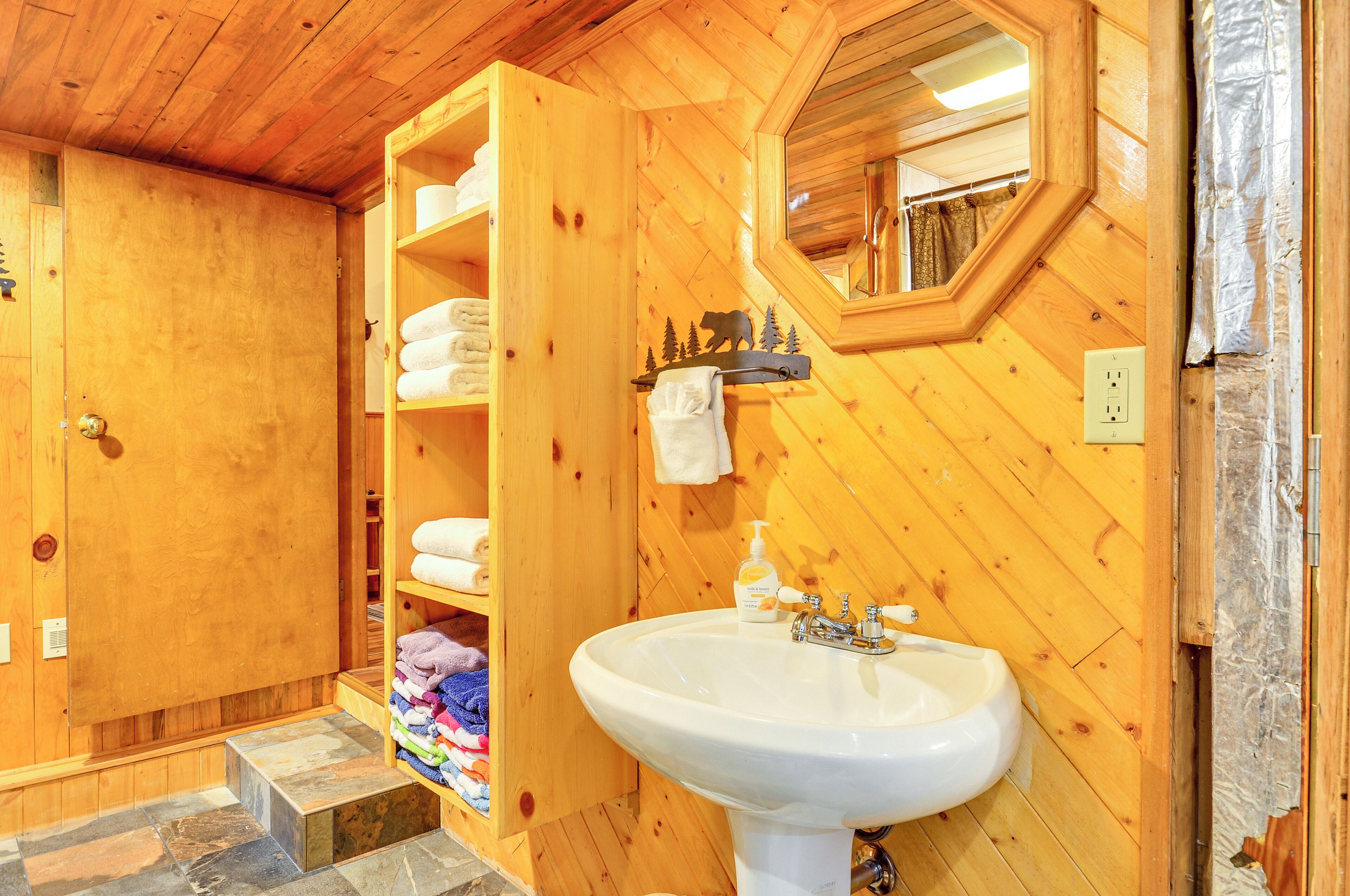 A wooden bathroom with a large sink, towel racks, and a mirror.