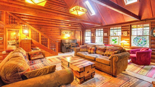 A log cabin interior with a cozy living area, wooden walls, and a staircase. - Forested 'minikahda Lodge' w/ Hot Tub Near Mt Hood (Rhododendron)