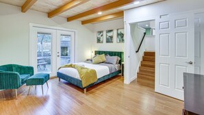 Een slaapkamer met een bed, een groene stoel, een houten vloer en een trap.