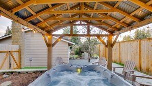 Een hottub onder een houten pergola, omringd door stoelen.