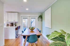 Een moderne keuken met witte kastjes, een marmeren eiland en een houten eettafel met stoelen.