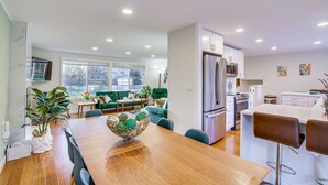Een moderne keuken met een eethoek, met een houten tafel, barstoelen en een grote decoratieve schaal.