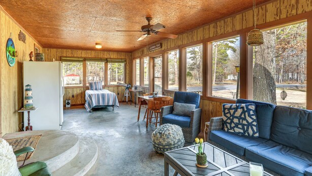A spacious room with a wooden ceiling, large windows, a sofa, a dining table, and a ceiling fan. - Pet-friendly Higden Getaway < 1 Mi to Marina! (Higden)