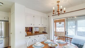 A dining area with a wooden table set for six, white cabinets, a refrigerator, and a large window with a view. - Pet-friendly Higden Getaway < 1 Mi to Marina! (Higden)
