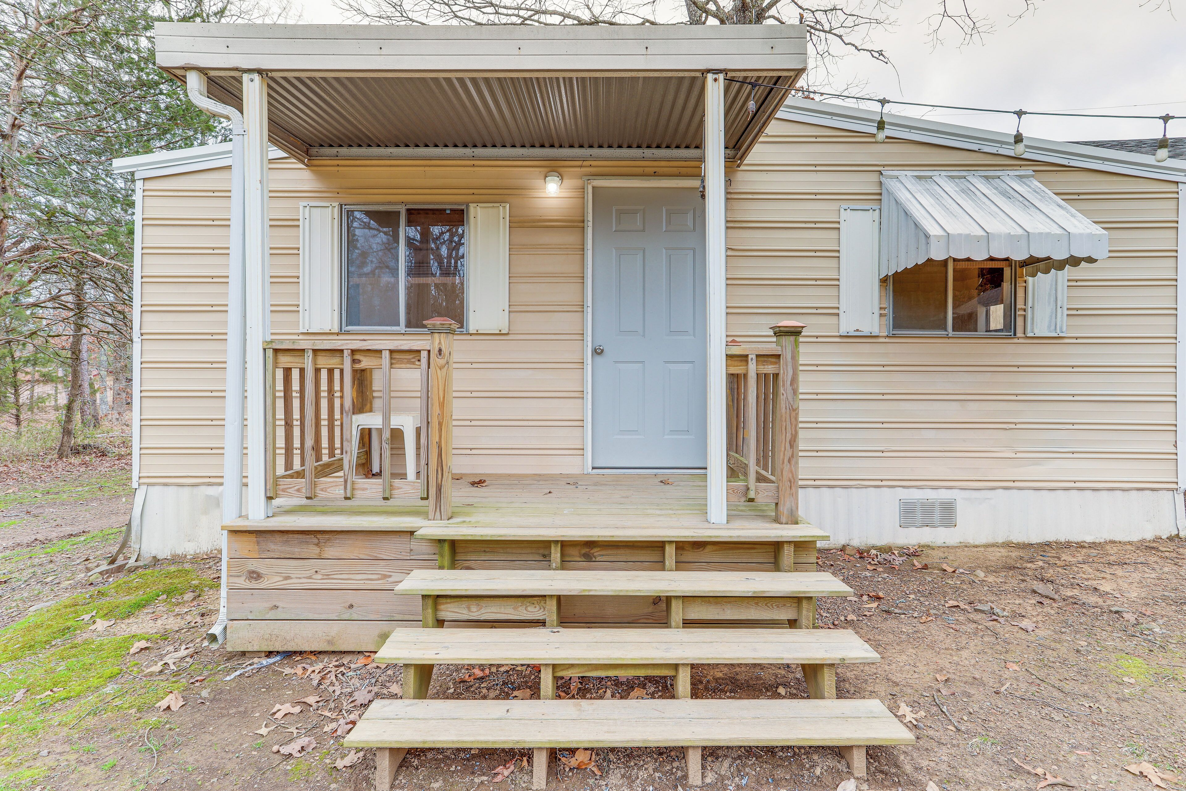 A small wooden cabin with a porch, a front door, and a window with shutters.