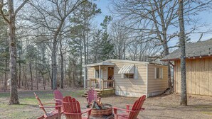 A cabin with a fire pit and red Adirondack chairs in a wooded area. - Pet-friendly Higden Getaway < 1 Mi to Marina! (Higden)