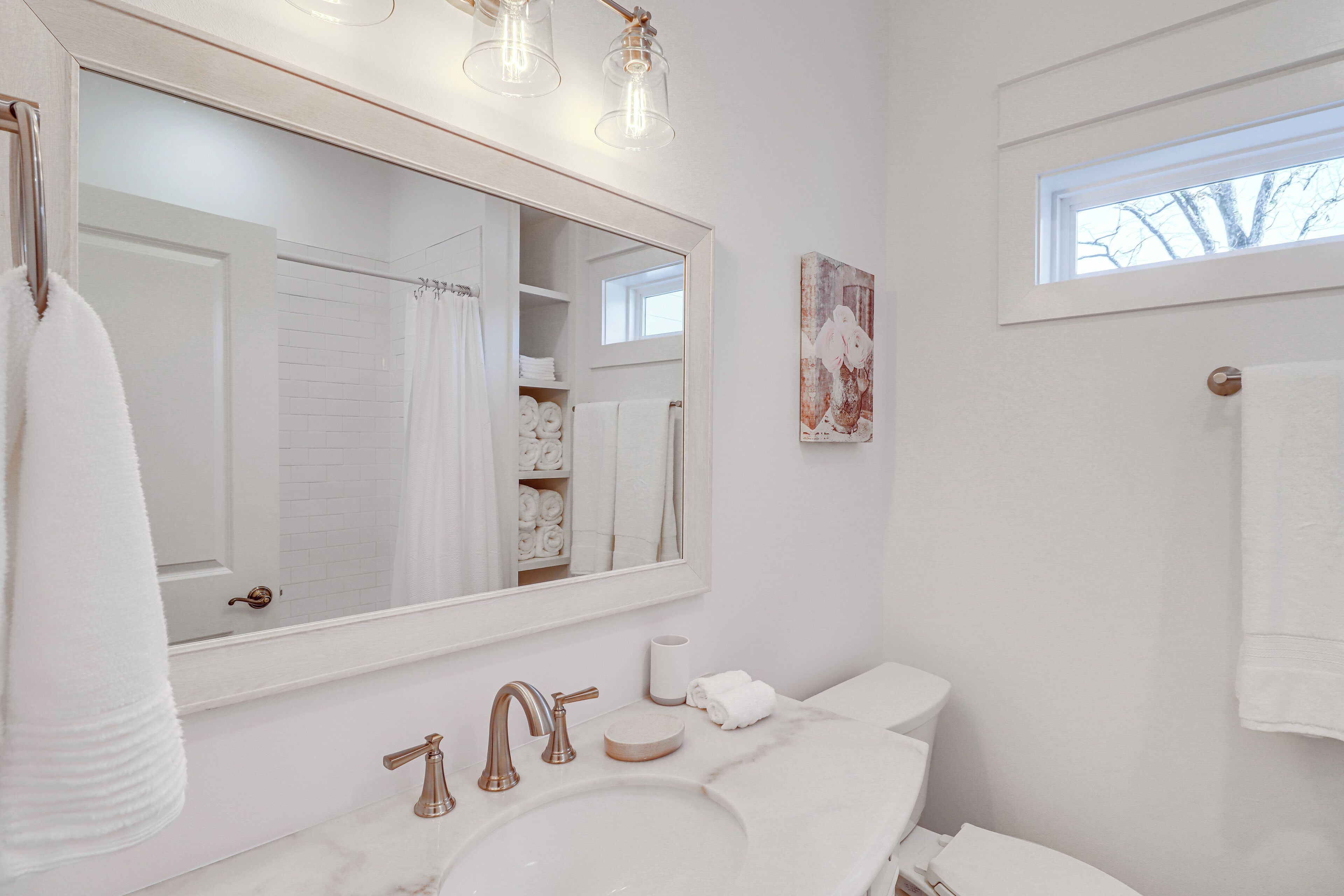 A bathroom with a large mirror, white sink, and towel rack.