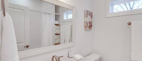 A bathroom with a large mirror, white sink, and towel rack.