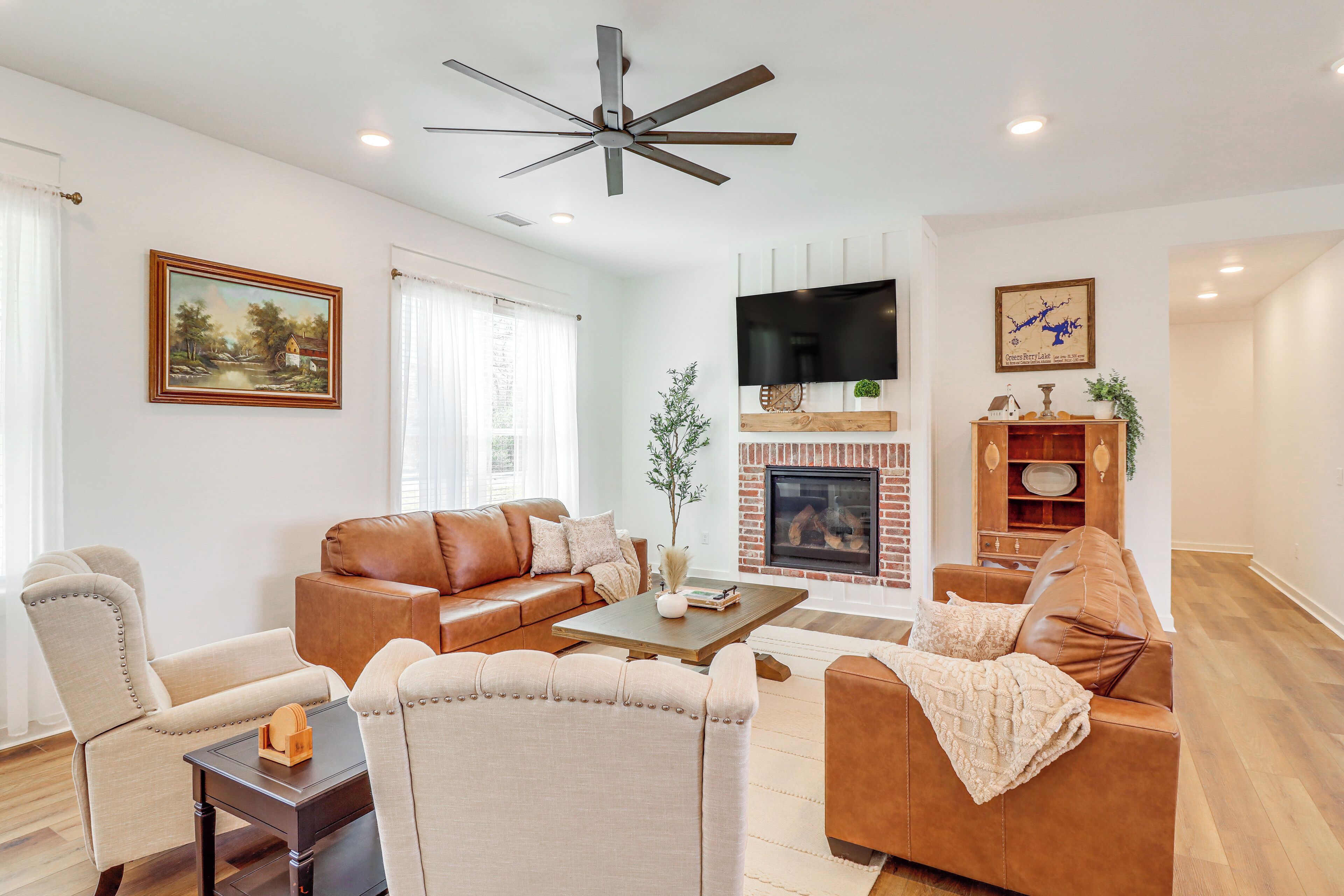A living room with a fireplace, leather sofas, a coffee table, and a television mounted on the wall.