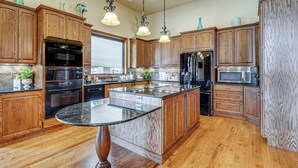 A spacious kitchen with wooden cabinets, a central island, and modern appliances. - Colorado Springs Home ~ 4 Mi to Garden of the Gods (Colorado Springs)