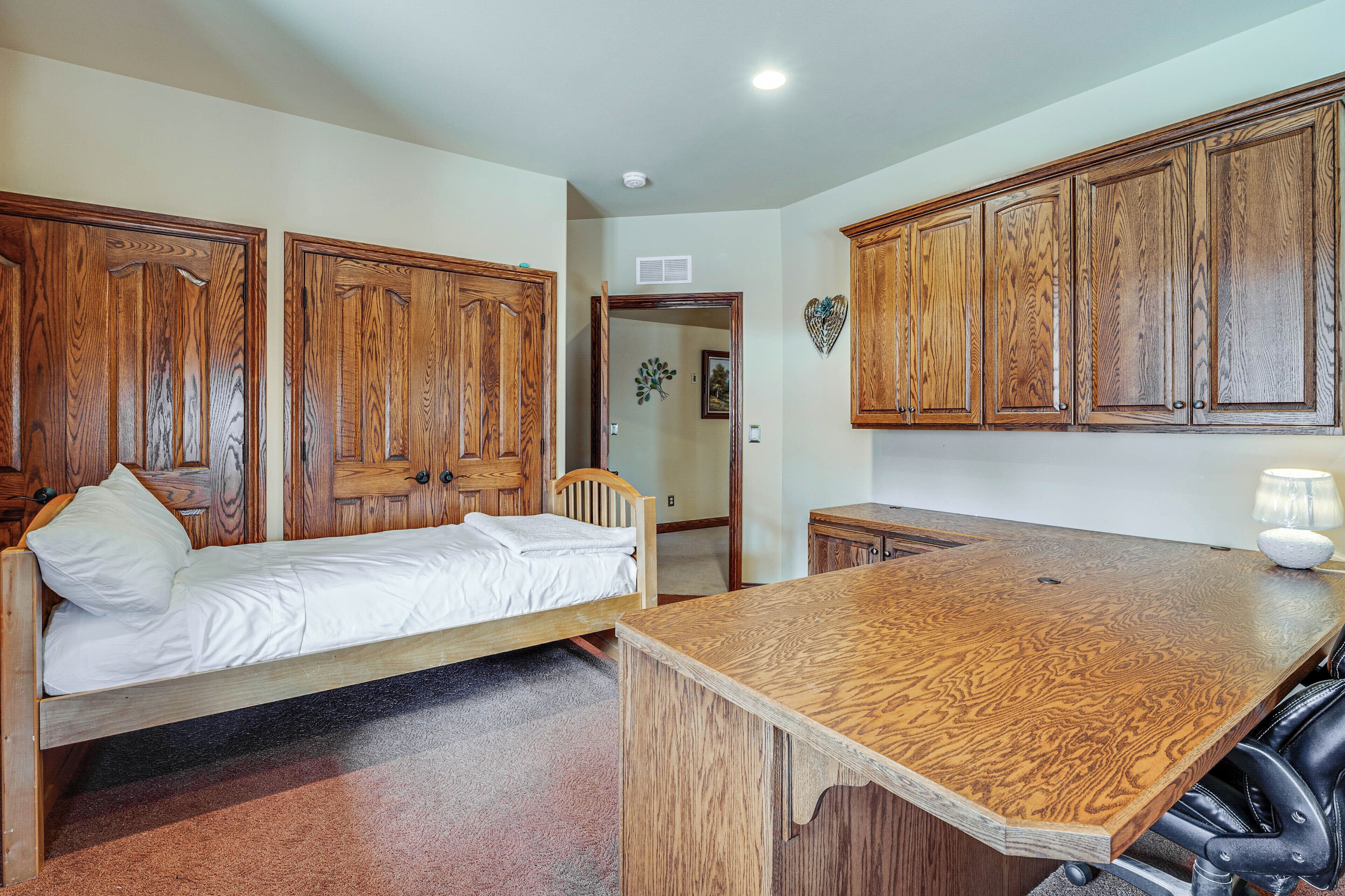A bedroom with a wooden bed, a wooden desk, and a wardrobe.