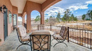 A covered patio with outdoor seating, a view of the surrounding landscape, and a brick wall. - Colorado Springs Home ~ 4 Mi to Garden of the Gods (Colorado Springs)