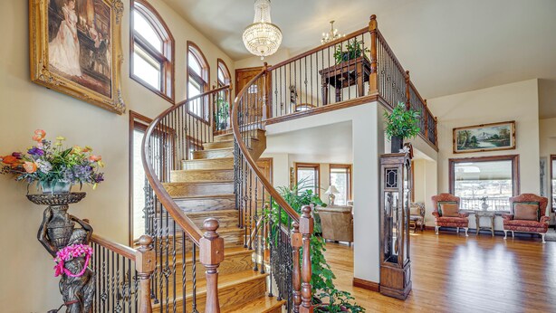 A spacious living area with a wooden staircase, large windows, and a chandelier. - Colorado Springs Home ~ 4 Mi to Garden of the Gods (Colorado Springs)