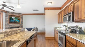 A kitchen with granite countertops, wooden cabinets, a microwave, and a dishwasher. - Chalakee Lodge CA-3- Mountain View, Gated Resort, Indoor/Outdoor Pools & Hot Tub (Boone)