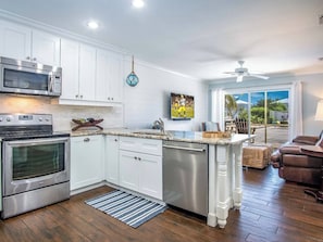 A kitchen with white cabinets, stainless steel appliances, a wooden island, and a view of the outdoors.