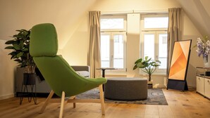 Un salon moderne avec un fauteuil vert, un pouf gris et une plante en pot.