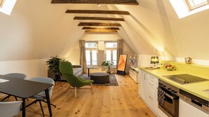 Un appartement moderne de style «loft» comprenant un coin repas, une cuisine et une grande fenêtre.